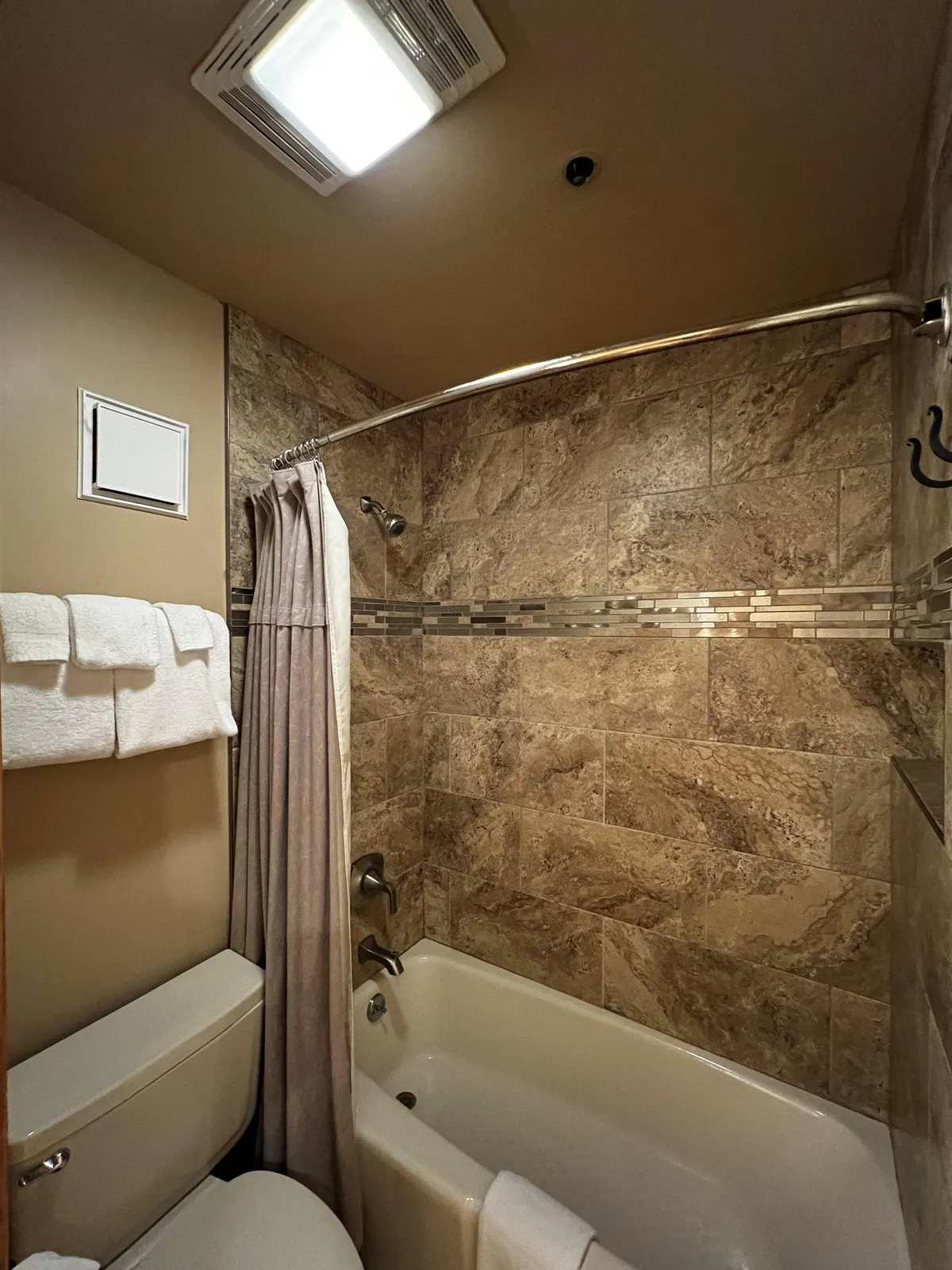 This image showcases a clean and inviting bathroom space featuring a bathtub with a shower curtain, neatly arranged towels, and stylish tiles. The overall mood is calm and refreshing, suggesting a private spot to unwind after outdoor adventures or prepare for a day of exploration.