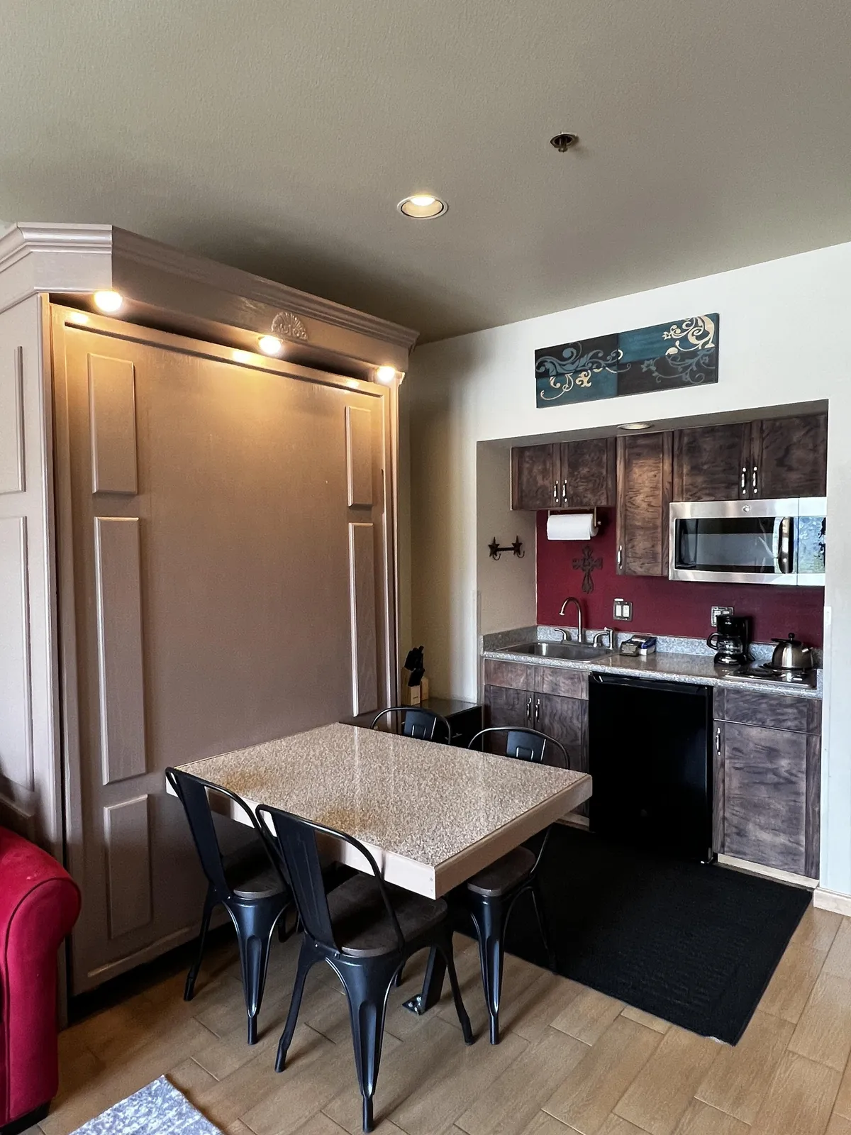 A cozy and functional space featuring a dining table, kitchen area, and a Murphy bed, designed for family meals or entertaining guests. The setup encourages social interaction, sharing stories, and enjoying coffee, all in an inviting atmosphere.
