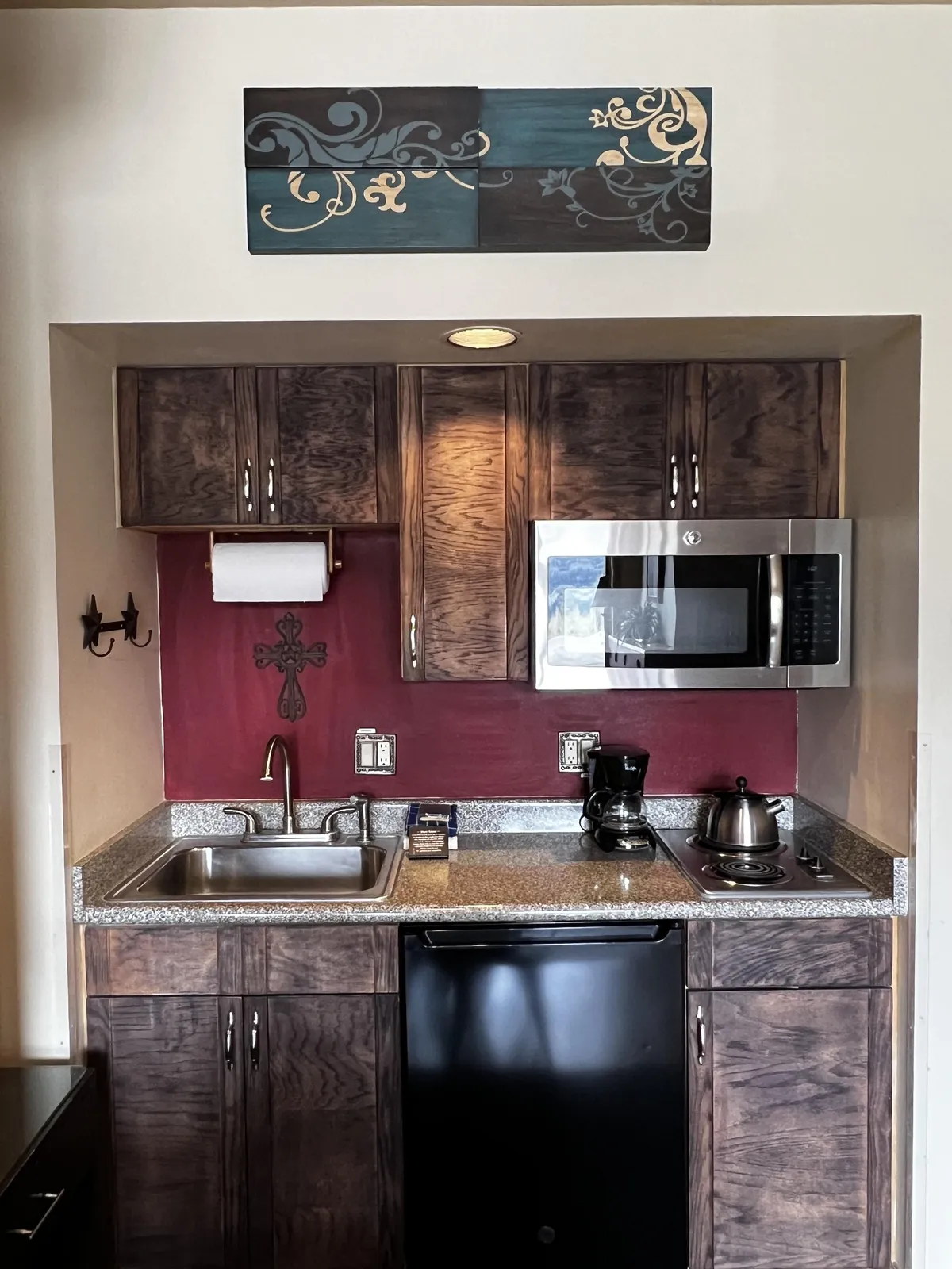 A warmly-lit kitchen with decorative wall art, modern appliances, a sleek sink, and inviting cabinetry. The space feels cozy and intimate, perfect for two people to share a morning coffee or prepare a meal together while taking in glimpses of the mountain scenery through the window.