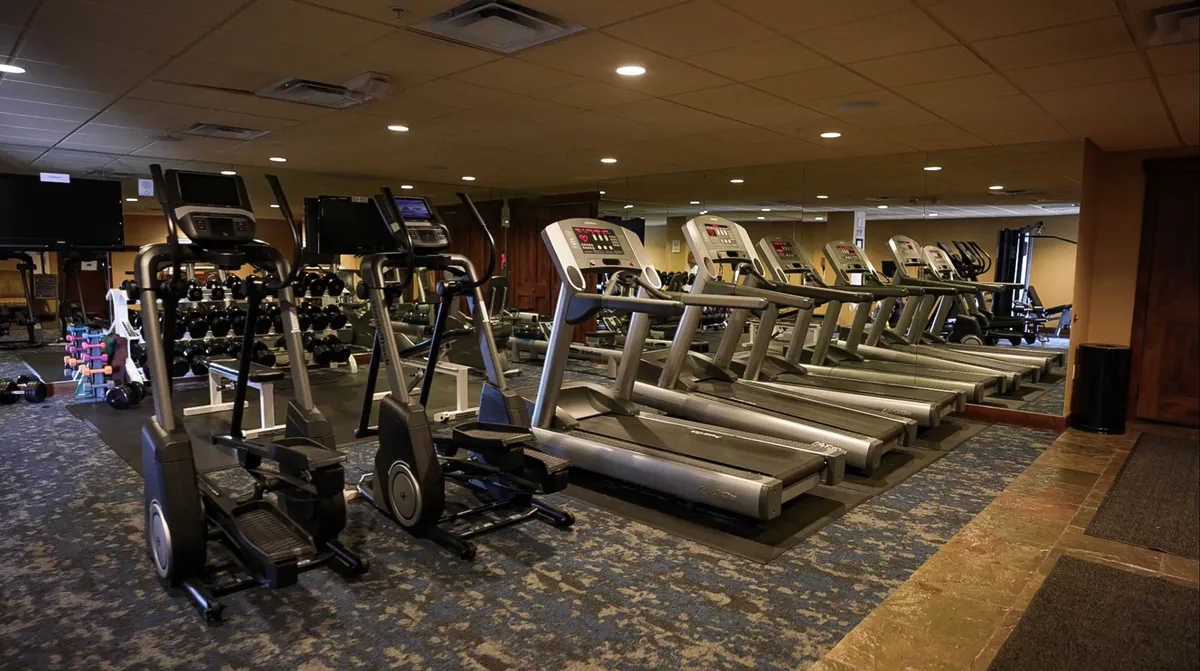 A well-equipped fitness center with treadmills, ellipticals, dumbbells, and ample space for cardio and strength training. The environment feels motivational, encouraging guests to maintain their health and fitness routines as part of their stay.